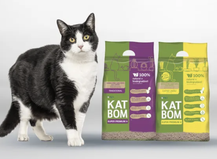 Tuxedo cat sitting next to a bag of Katbom natural cat litter